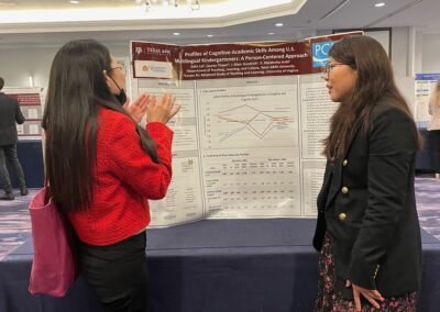 Two students discussing a research poster posing in front of the poster.