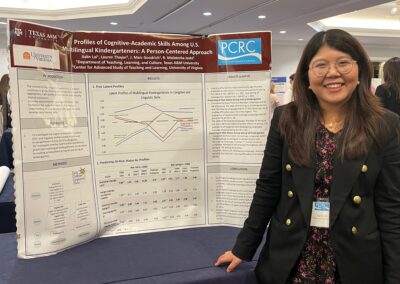 Research student standing by her research poster smiling.
