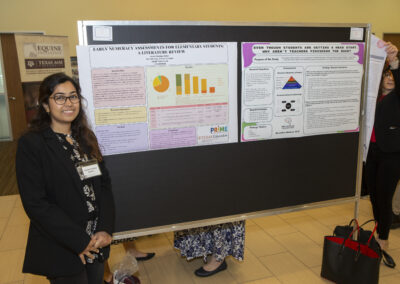 Research presenter posing in front of her research poster at the 2025 Early Childhood Summit.