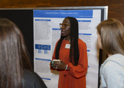 Woman presenting her research poster at the 2025 Early Childhood Summit.