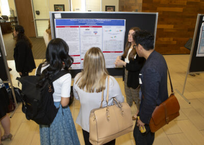 Research presenter showing her research poster to a small group at the 2025 Early Childhood Summit.