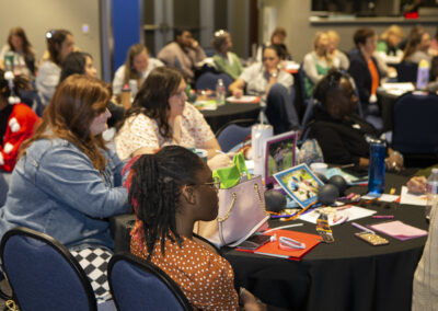 Medium shot of audience members listening to a presenter at the Texas Play & Development Conference.
