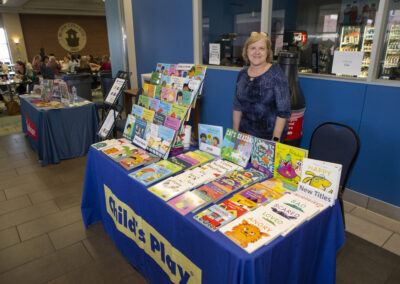 Woman posing with children's book at her booth at the Texas Play & Development Conference.