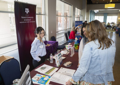 Woman at a booth speaking with participants at the Texas Play & Development Conference.