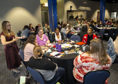 Dr. Gerde speaking to a group of people sitting at a table at the Texas Play & Development Conference.